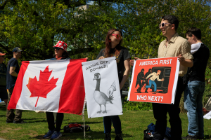 Three protesters with a large Canadian flag, the angry goose and the abduction signs.